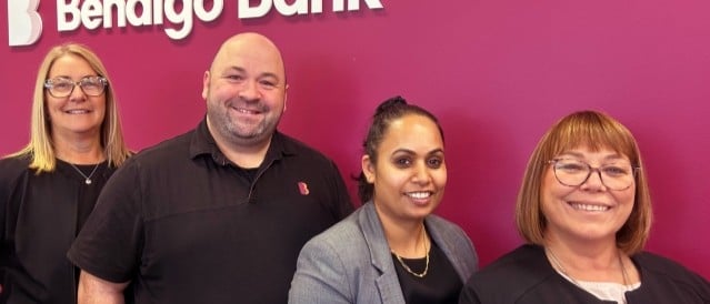Group of staff standing in front of a plum-coloured background