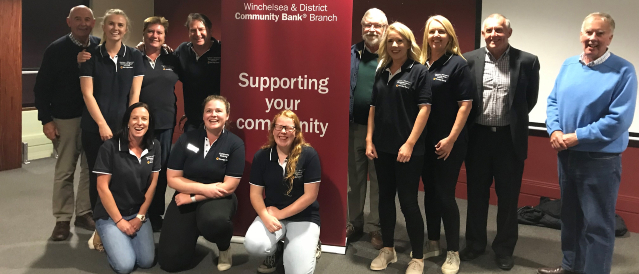 A group of staff and directors posing in front of a Community Bank Winchelsea & District banner on the evening of a health night.   