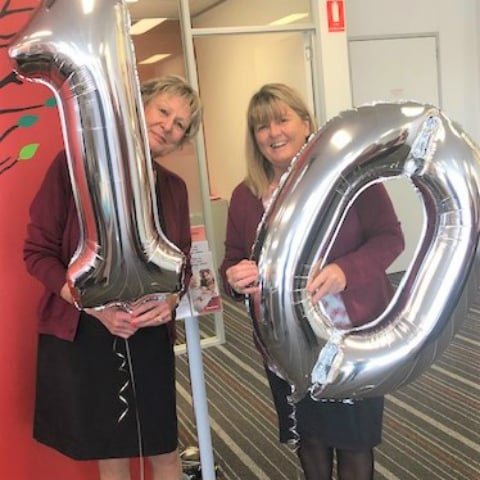 Two branch staff members from Heidelberg Community Bank Branch holding silver balloons in the shape of number 10.