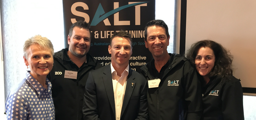 Representatives from SALT group standing in front of a branded SALT banner.