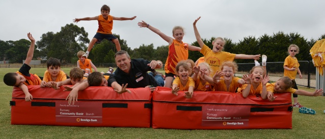 Picture of the little athletics team jumping on newly provided jump mats with the Romsey branch manager - mats supplied by Community Bank Romsey