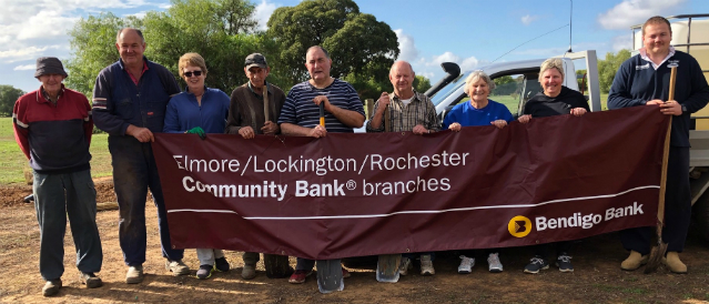 Rochester Cemetery Trust members receive a grant and stand with a Elmore, Lockington, Rochester Community Bank Branch banner at the local cemetery.