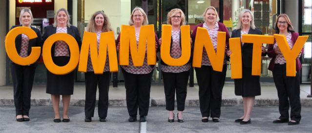 Logan Village and Jimboomba branch staff holding COMMUNITY letters.