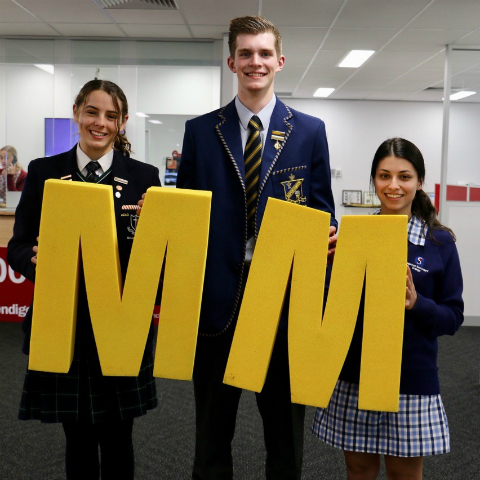 Students holding community letters M and M to represent the Magic Moments program.