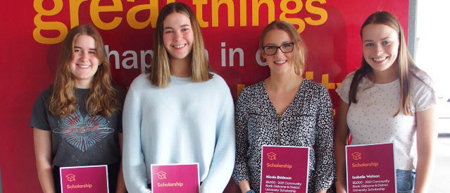 Four student scholarship recipients smiling while holding certificates.