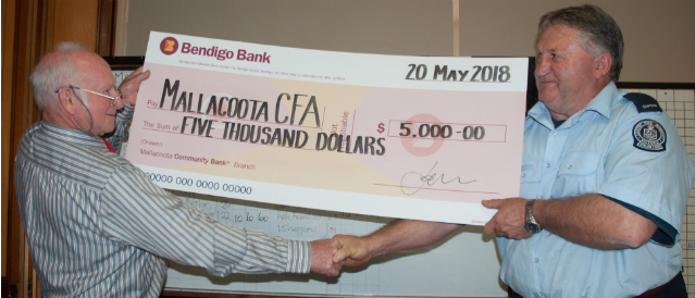 Representative from the Mallacoota CFA receives a cheque from a director of Mallacoota Community Bank Branch.