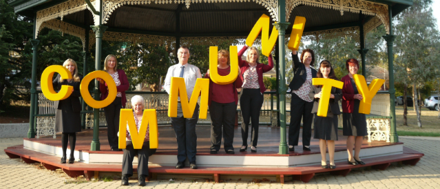Mooroolbark Community Bank Branch staff standing on a gazebo holding large yellow letters spelling out the word 'community'.