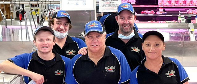 Five smiling essential workers at local butcher shop