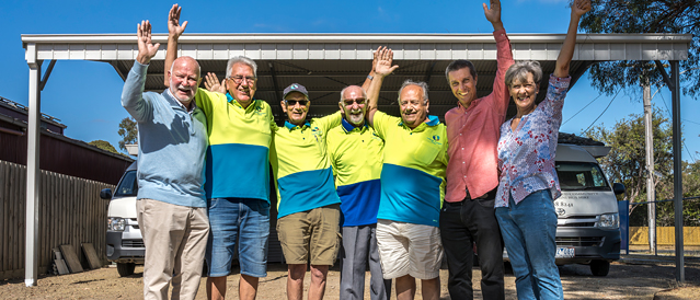 A group of people standing in front of a bus port and two minibuses