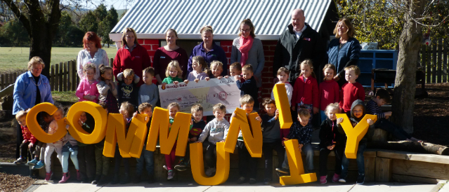 A group of people holding a novelty cheque and big yellow letters spelling the word 'community' in recognition of a recent Bungendore Community Bank Branch grant. 