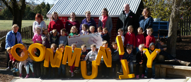 A group of people holding a novelty cheque and big yellow letters spelling the word 'community' in recognition of a recent Bungendore Community Bank Branch grant.