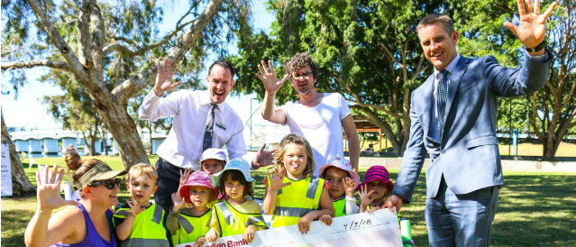 Branch staff and directors with young children holding a novelty cheque recognising a grant from Paradise Point Community Bank Branch.