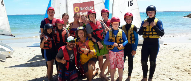 Kids on the beach in front of sailing boats funded by Robe and District Community Bank Branch.