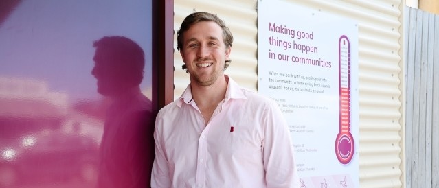 A man standing in front of a sign with a tally of contributions made