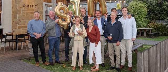 A group of people holding up gold balloons