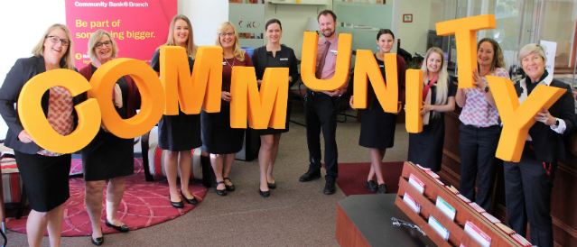 Cooroy branch staff group photo holding COMMUNITY letters.