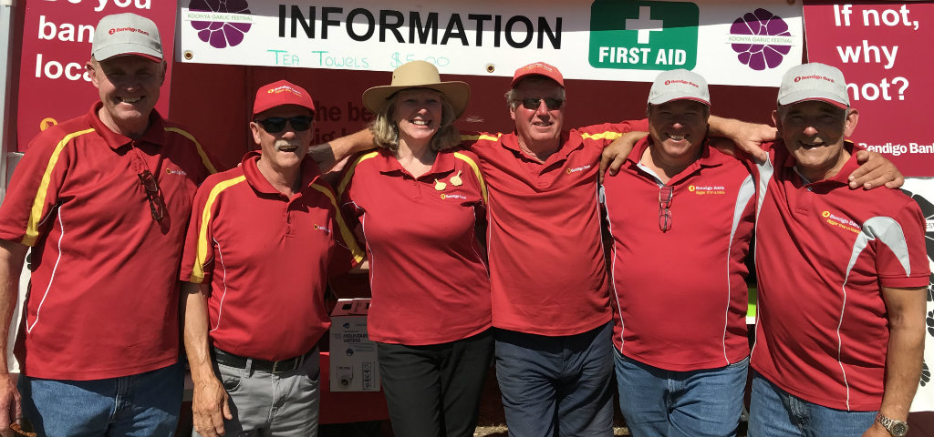 Group of branch representatives wearing Bendigo Bank branded polo tops and caps at local event.
