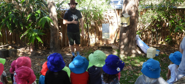 Group of young students sitting outdoors and learning about flora and fauna.