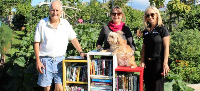 People pictured with a bookshelf of books to promote the new little lending libraries supported by Bendigo Bank Tugun.