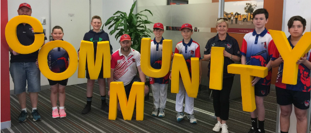 Representatives from clubs which have received funding from Doreen Mernda Community Bank Branch holding large yellow letters spelling out the word community.