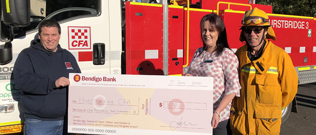 A Community Bank staff member presents a big cheque to the Hustbridge CFA in front of a fire engine