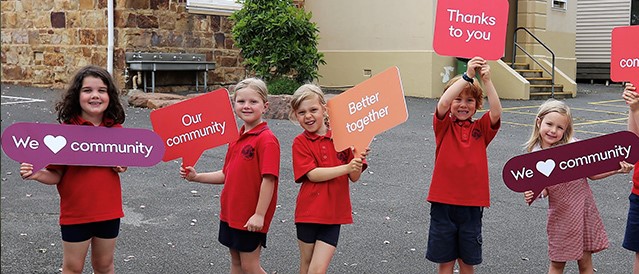 Primary school students holding community signs