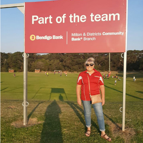 Branch representative standing in front of a Bendigo Bank sponsorship sign.