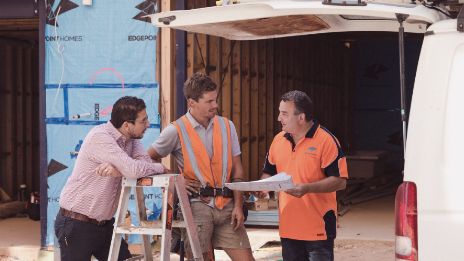 Business owner and staff talking at the back of a work vehicle