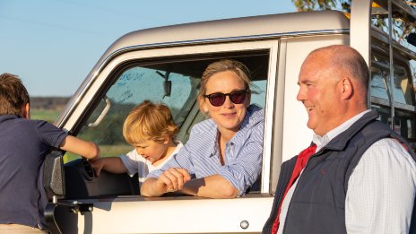 Female farmer with two young children sitting in a a ute talking to an agribusiness specialist 