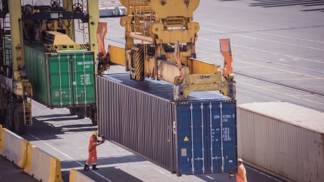 Photo of shipping container being loaded onto the wharf by crane. 