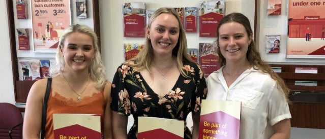 Three young female Community Bank scholarship recipients holding their scholarship packs.