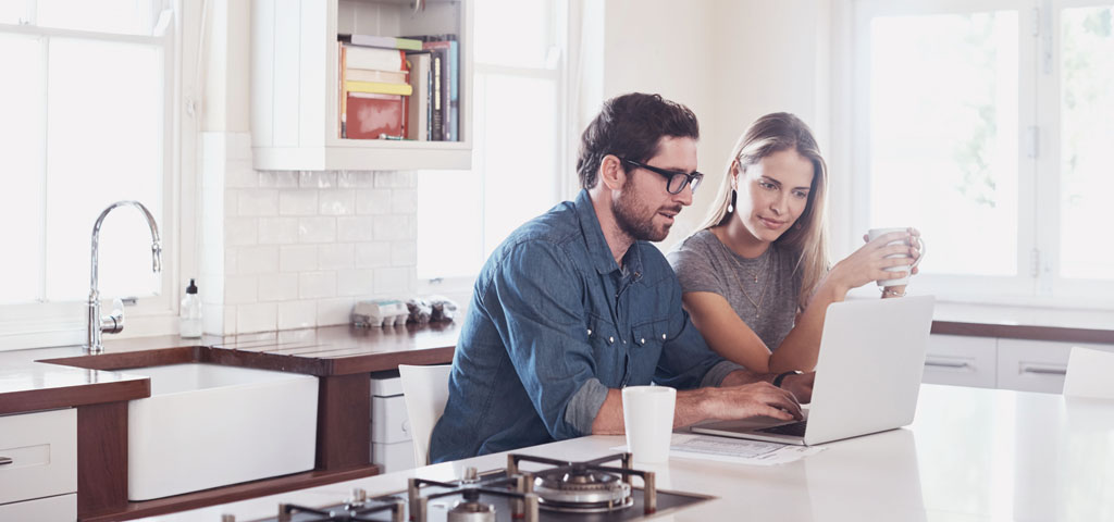 A couple using a laptop in the kitchen