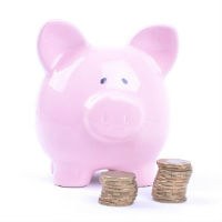 Pink piggy bank with two stacks of coins in front of it.