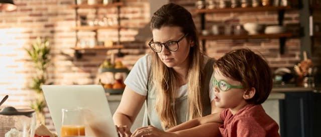 Mother and son at kitchen table looking up home loans on their laptop.