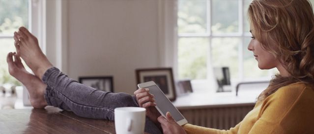 A person sitting at their table while using a mobile device.