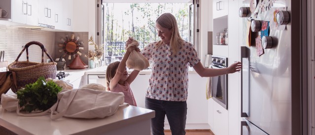 A mother and child standing in their kitchen.