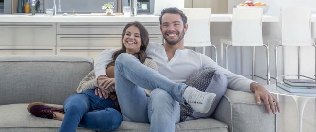 Tenants relaxing on their sofa in their rental property which their landlords have covered.