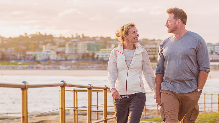 Fit and healthy middle-aged couple walking along the shorefront.