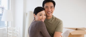 Middle-aged couple hugging in their new home looking happy that they have achieved their financial goal.