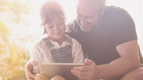 Father showing daughter how to use tablet.